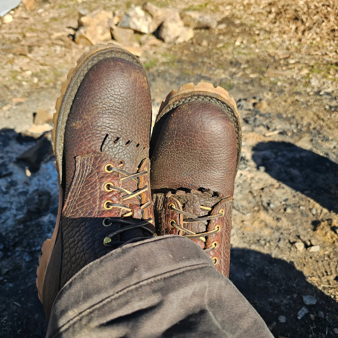 Pair of O.T. Bison work boots on feet on rocky ground