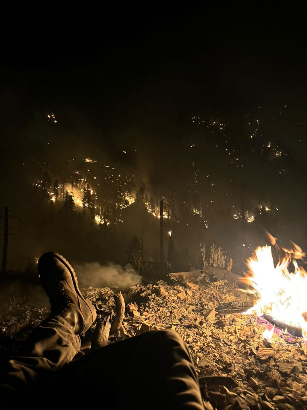Wildland Firefighter loaded with gear, propping his thick leather boot on his chainsaw