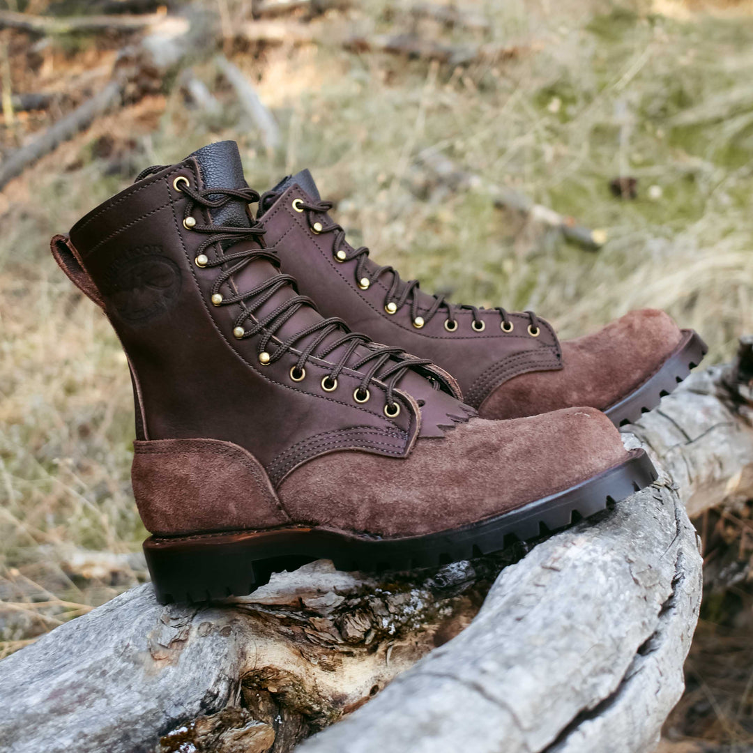Side view of a pair of OT Pro brown leather work boots on a log