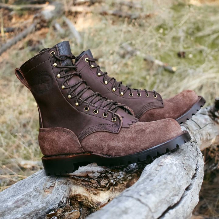 Side view of a pair of OT Pro brown leather work boots on a log
