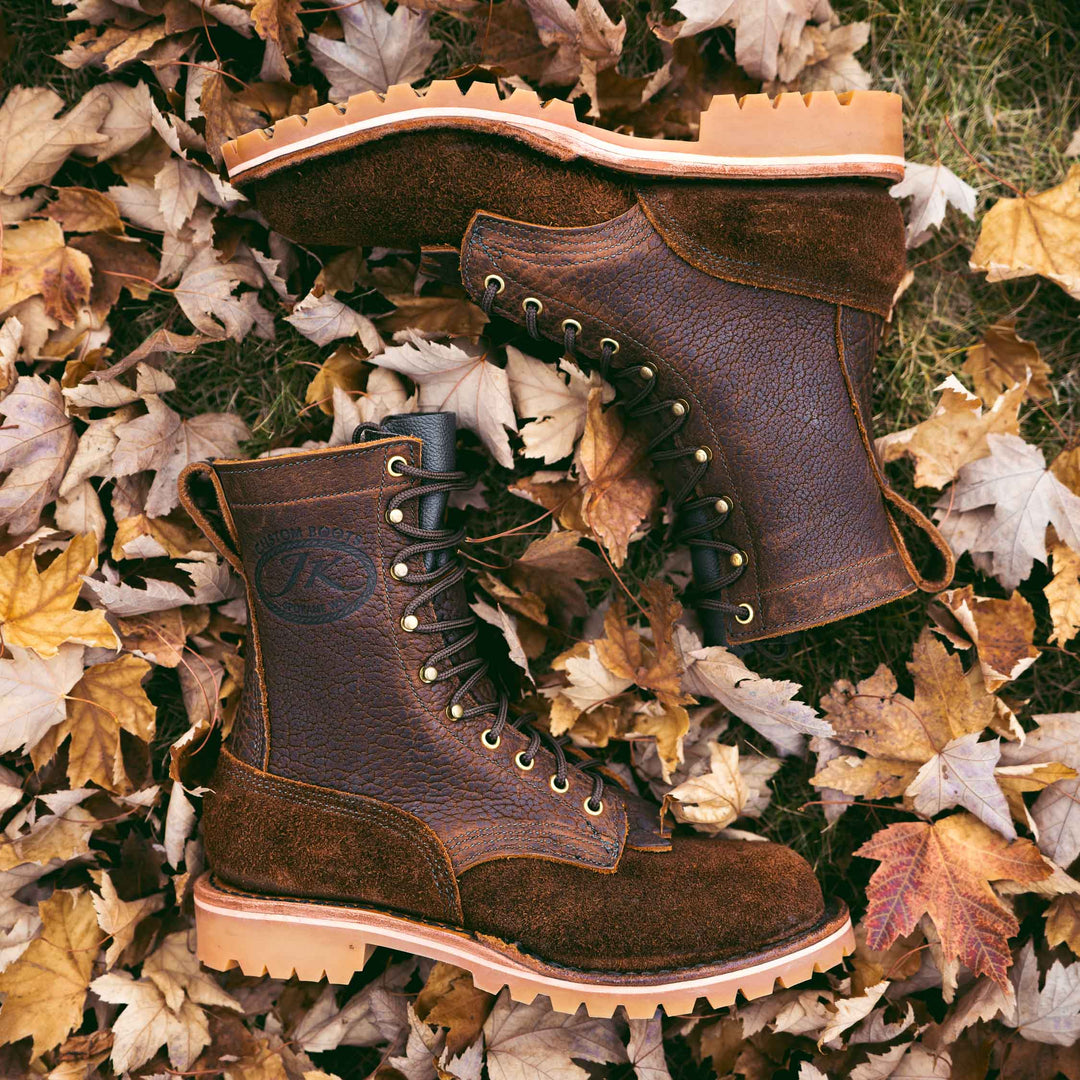 Pair of OT Bison rough leather work boots on grass and dry leaves