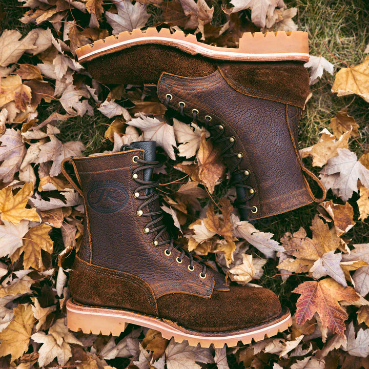 Pair of OT Bison rough leather work boots on grass and dry leaves