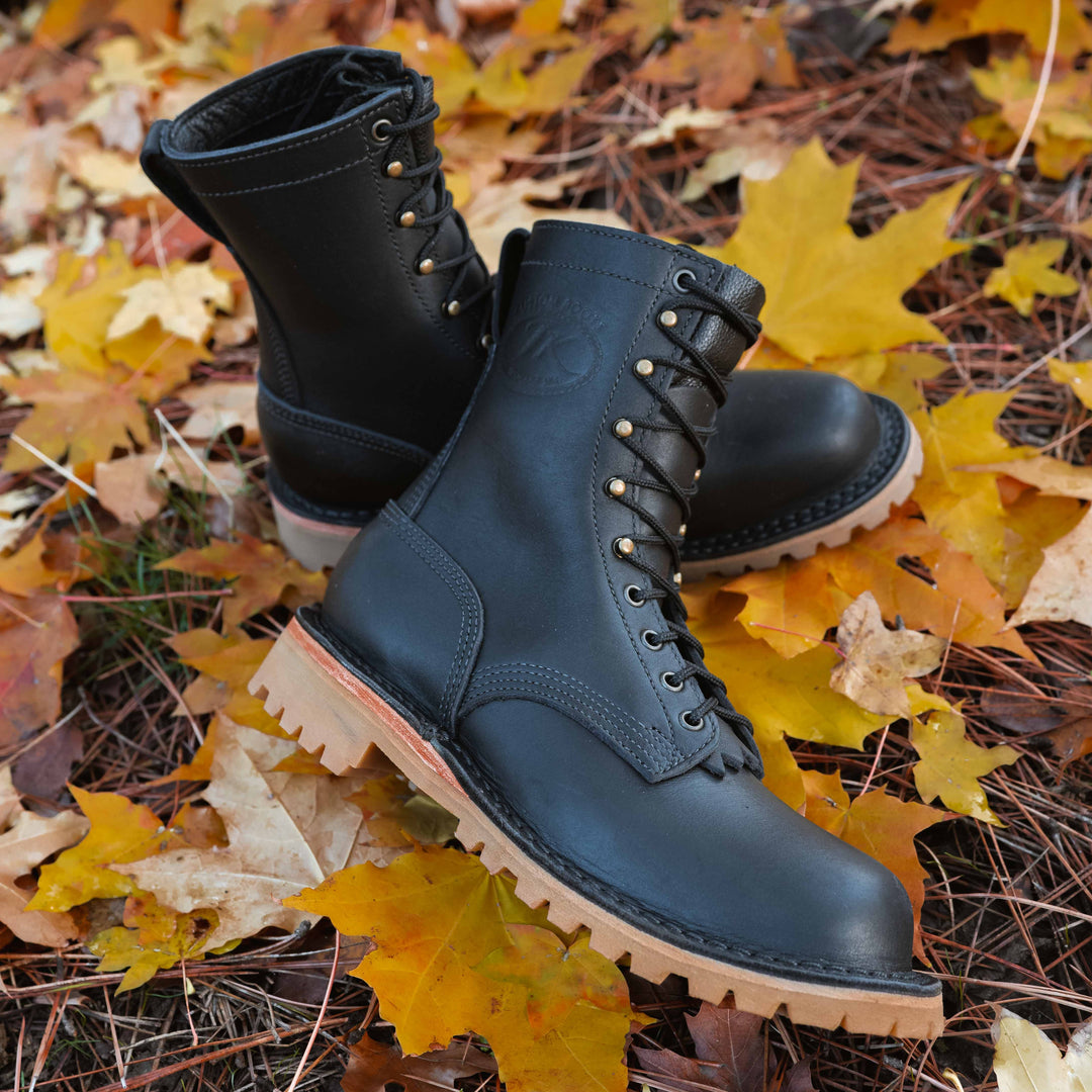 Pair of OT Black leather work boots on autumn leaves
