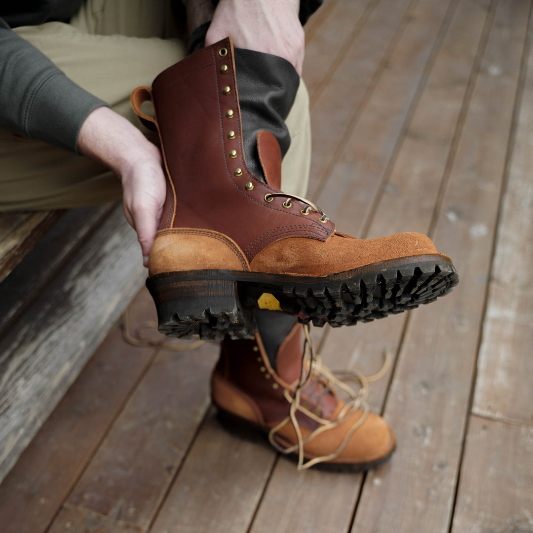 Person sitting and putting on a pair of redwood rough leather work boots
